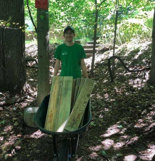 Jacob Adams '21 holds wheelbarrow filled with lumber